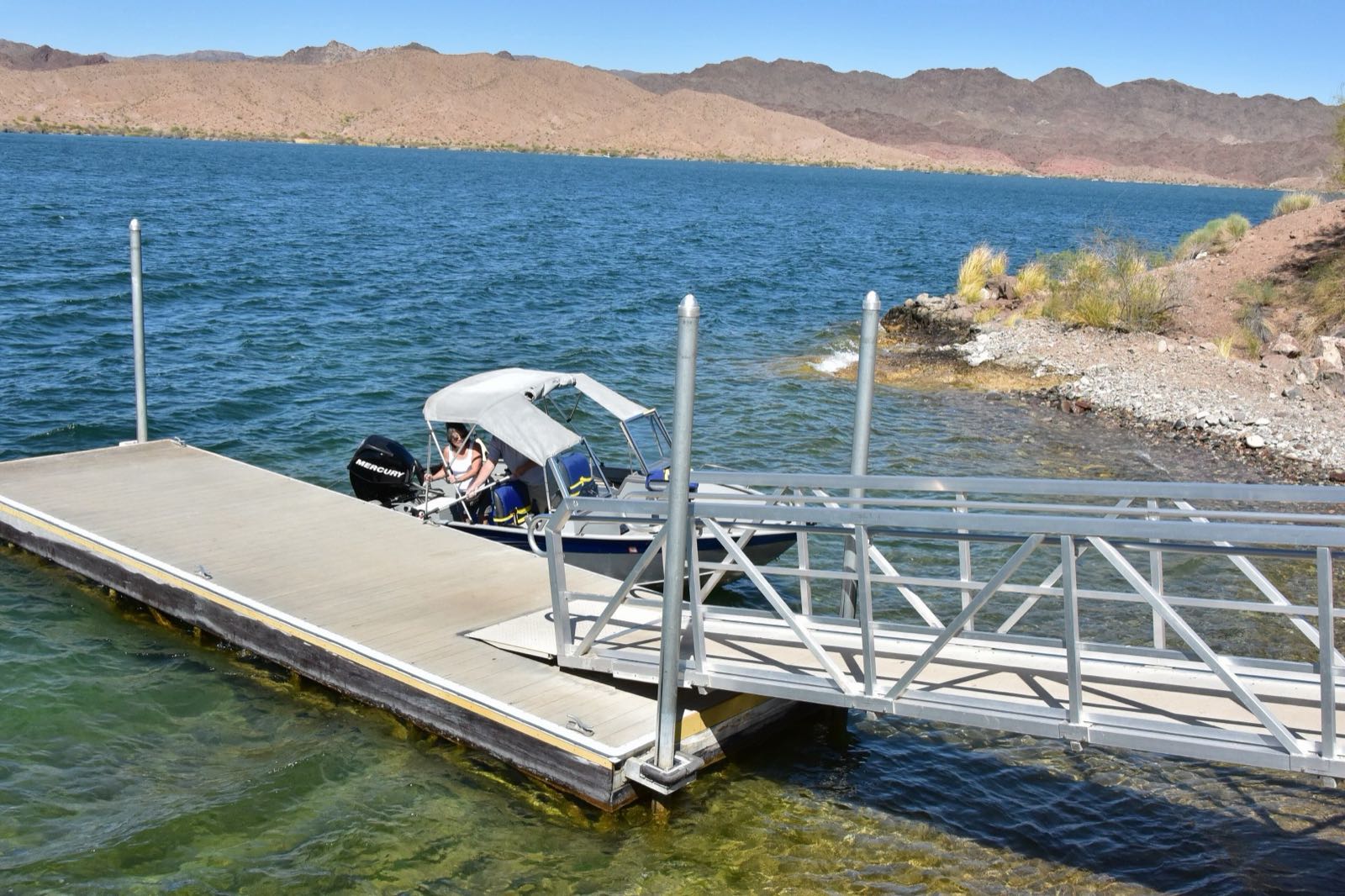 A boat tied up at a dock on Lake Havasu with the mountains behind