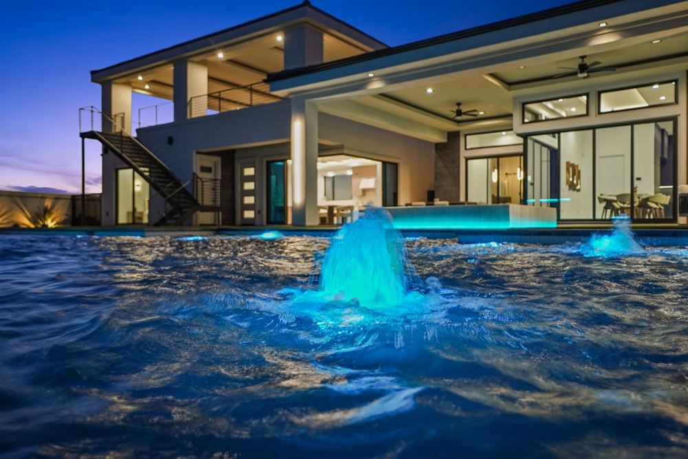 Pool fountain at dusk with the back of the home lit behind it