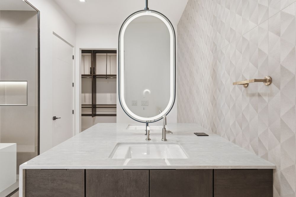 Primary bath vanity with an oval lit mirror
