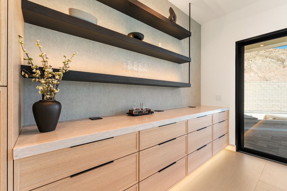 Bar with lit floating shelves beside a sliding door