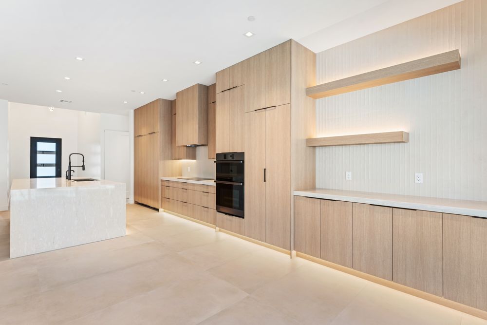Wall of wood cabinetry with lit floating shelves